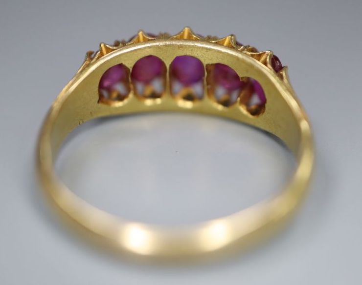 A yellow metal and graduated five stone ruby set half hoop ring,